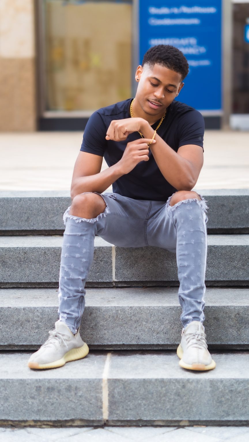Showcasing street style, Tyler Jurelle wears Yeezy Boost 350 V2 Sneakers and Craftd London jewelry.
