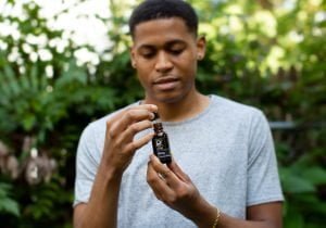 Tyler Jurelle’s face is visible as he displays a Physicians Grade CBD product, focusing on its premium packaging.
