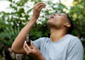 Tyler Jurelle’s face is visible while hand-modeling a Physicians Grade CBD tincture, demonstrating its use.