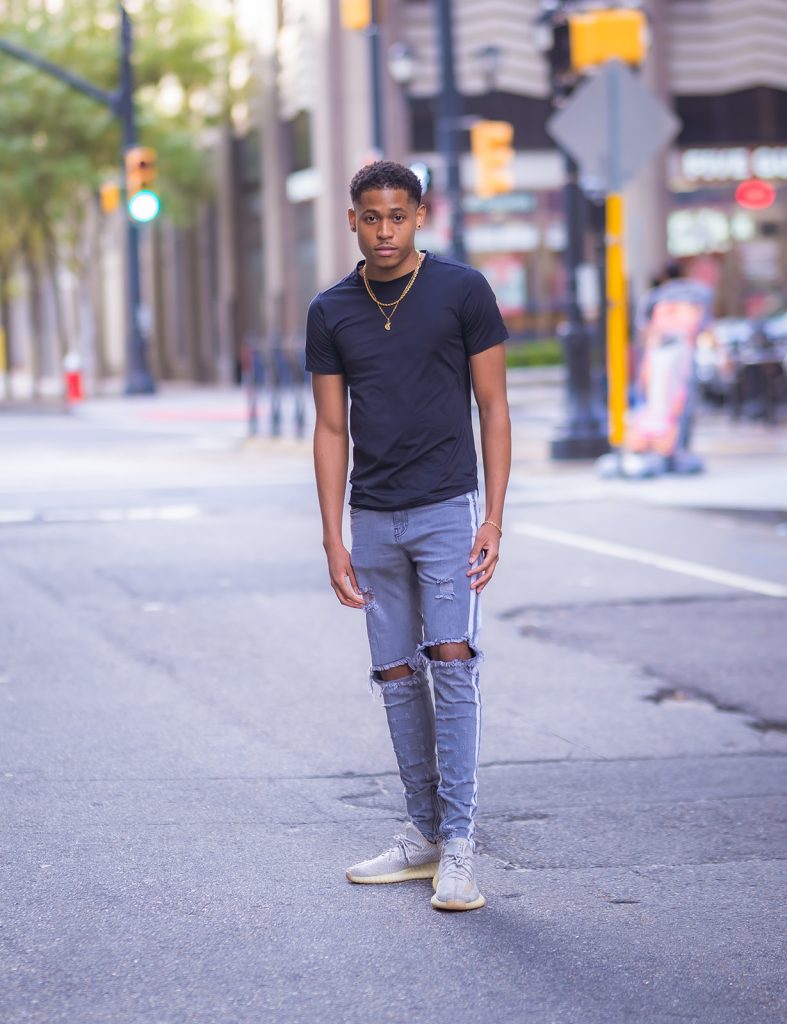 Capturing everyday style, Tyler Jurelle in a black T-shirt and PRSTGE track jeans.