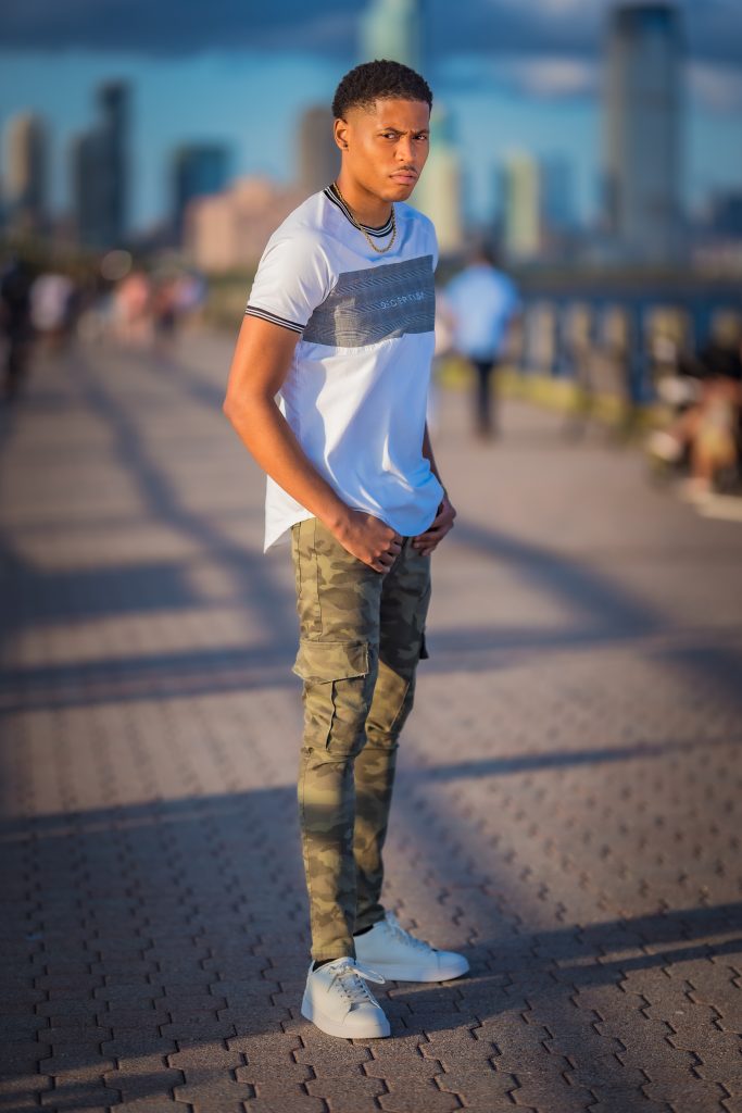 Tyler Jurelle styled in a Deception Toronto Miami Plaid Tee, Cesar Military Cargo Jeans, and Zara plain white sneakers, photographed in Liberty State Park.