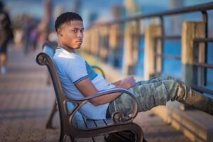 Tyler Jurelle is sitting casually in Deception Toronto Cesar Military Cargo Jeans, highlighting the relaxed fit and style captured in Jersey City.