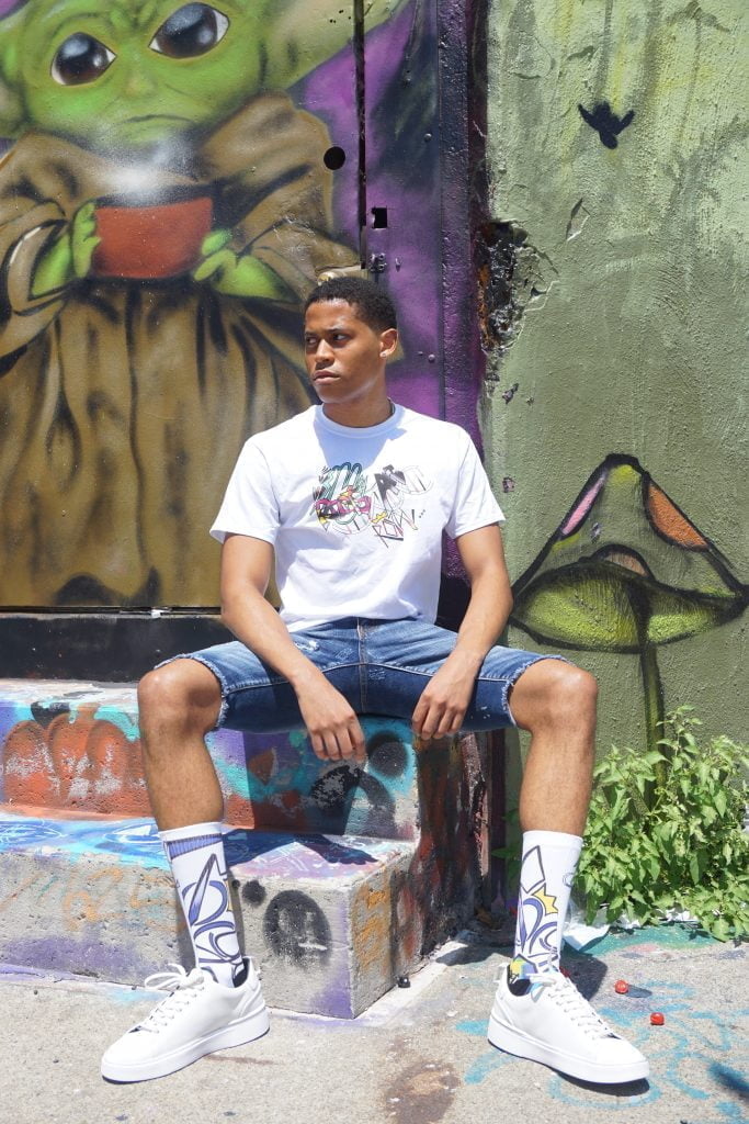Relaxed and stylish, Tyler Jurelle sits on steps in Royal One Soul streetwear, embodying laid-back street fashion.
