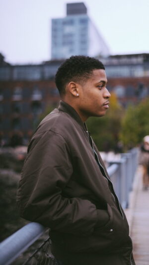 Confident in an olive bomber jacket, Tyler Jurelle captures the essence of Brooklyn Bridge Park.