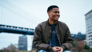 Tyler Jurelle takes a break in an olive bomber jacket at Brooklyn Bridge Park.