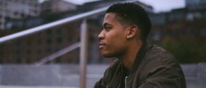 Reflecting on the day in a stylish bomber jacket at Brooklyn Bridge Park.
