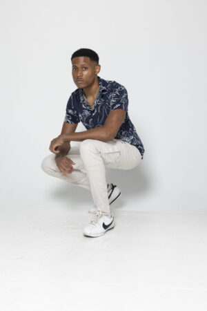 A laid-back pose in a studio featuring beige biker cargo pants and a blue shirt.