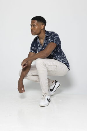 Men's fashion creator Tyler Jurelle is mixing casual chic with a blue shirt and beige pants, finished with white Nike sneakers.