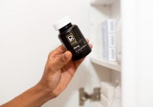 Hand holding a Physicians Grade CBD capsule bottle, showcasing its premium design.