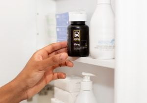 Hand-modeling a Physicians Grade CBD capsule bottle, emphasizing its sleek design.