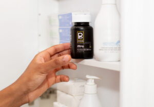 Hand-modeling a Physicians Grade CBD capsule bottle, emphasizing its sleek design.