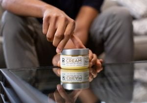 A hand arranges a Physicians Grade CBD skincare product, focusing on its high-quality packaging.