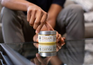 A hand arranges a Physicians Grade CBD skincare product, focusing on its high-quality packaging.