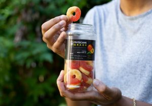 Close-up of Tyler Jurelle holding a Physicians Grade CBD gummies bottle and a single gummy, emphasizing the product’s quality.