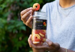 Close-up of Tyler Jurelle holding a Physicians Grade CBD gummies bottle and a single gummy, emphasizing the product’s quality.