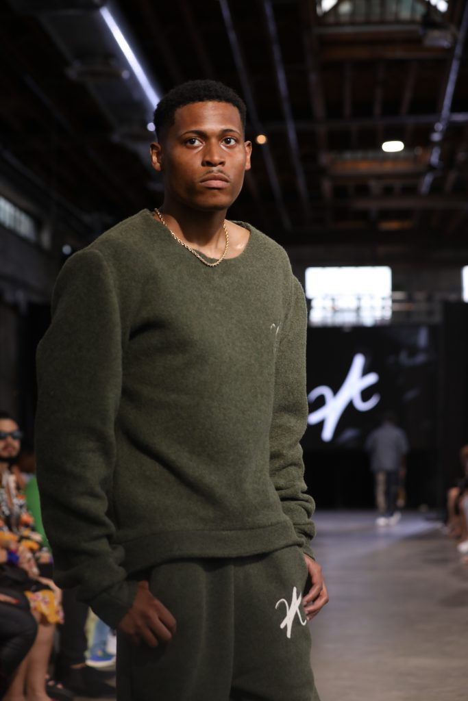 With a poised stride on the runway, Tyler Jurelle is showcasing Vaughn Acquis’s khaki green design.