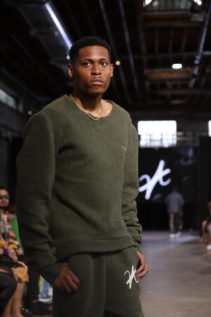 With a poised stride on the runway, Tyler Jurelle is showcasing Vaughn Acquis’s khaki green design.