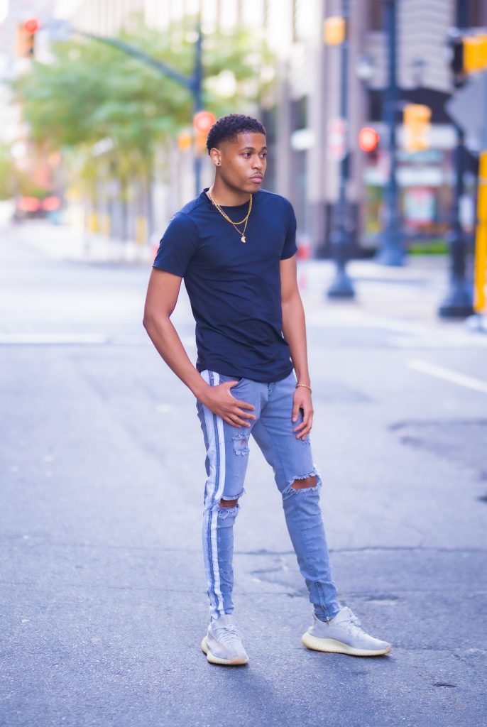 Lifestyle photoshoot featuring Tyler Jurelle in a basic black T-shirt and PRSTGE double stripe track jeans.
