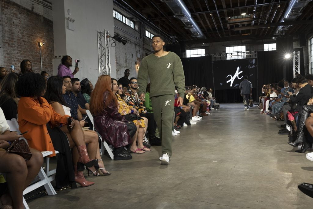 Tyler, the model, is exhibiting a powerful walk in a khaki green wool set, highlighting New York’s fashion energy.