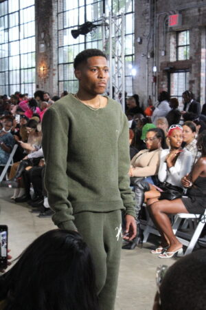 With vogue-worthy strides on the runway, Tyler Jurelle is dressed in Vaughn Acquis’s khaki green wool set.