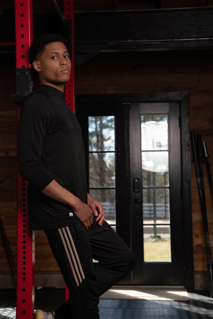 Lifestyle creator Tyler Jurelle is standing confidently against a metal column in Adidas athletic wear, ready for action.