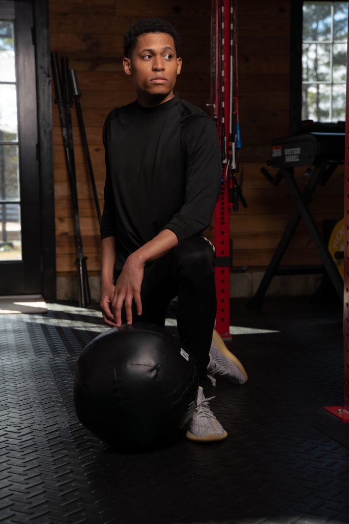 Kneeling with a 10-pound medicine ball, Tyler Jurelle is ready for the next move in a focused gym session.