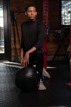Kneeling with a 10-pound medicine ball, Tyler Jurelle is ready for the next move in a focused gym session.