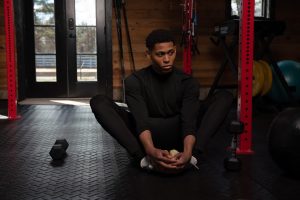 Seated on the gym floor in a butterfly stretch, Tyler Jurelle is centering the mind and body before his next workout. He is proactively trying to improve his overall health and wellness.