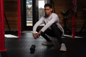 With a focused deep squat pose and a dumbbell by his side, Tyler Jurelle is emphasizing strength and balance. Check out Tyler Jurelle's full portfolio for all men's fashion and lifestyle content.