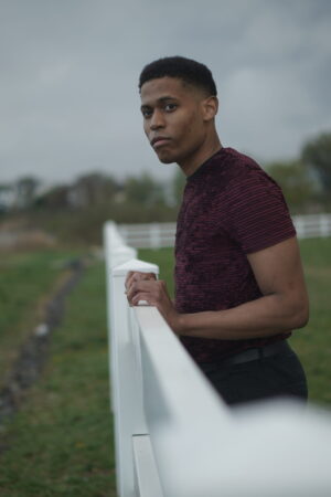 A relaxed and casual vibe is captured, featuring a burgundy t-shirt paired with black pants.