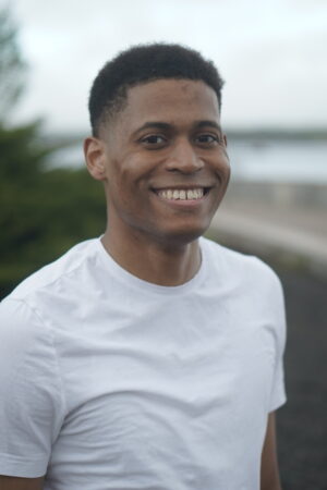 Close-up portrait of Tyler Jurelle in a white t-shirt, captured outdoors with natural lighting.
