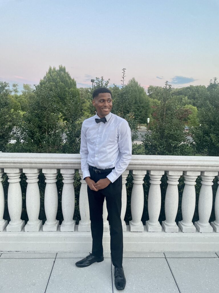 Tyler Jurelle’s polished look stands out as he removes the blazer, showcasing a crisp shirt and bow tie.