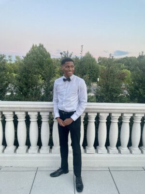 Tyler Jurelle’s polished look stands out as he removes the blazer, showcasing a crisp shirt and bow tie.