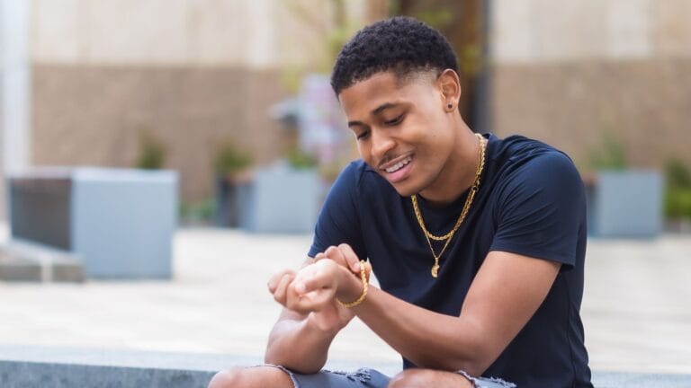 Men's lifestyle creator Tyler Jurelle is sitting outside, admiring his Craftd London men's jewelry.